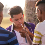 Youth culture young people group of male friends mixed race teen outdoor teenager in park. Hispanic kid smoking cigarette confident boy smoker. Health problems social issues.